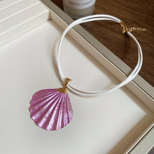 Detailed close-up of a pink shell pendant necklace with white double cords and gold accents