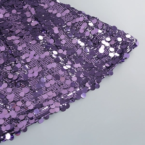 Detail der lila runden Pailletten auf einem Partykleid mit Lichtreflexion und Textur