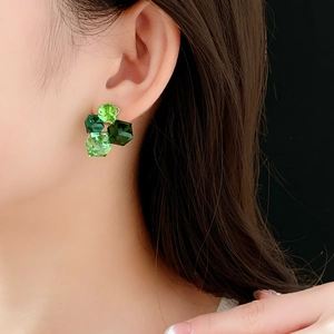 Detailed close-up of emerald green geometric hexagonal crystal stud earrings on model