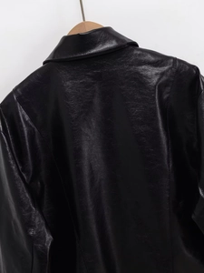 Detail of lapel and back stitching on black cropped faux leather jacket with wooden hanger