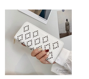 Detailansicht einer weißen Damen-Clutch mit schwarzen Nieten-Mustern und goldenem Reißverschluss