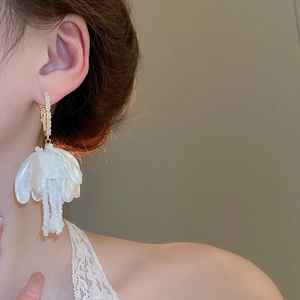 Detailed view of floral pearl tassel earrings with crystal studs and shell petals