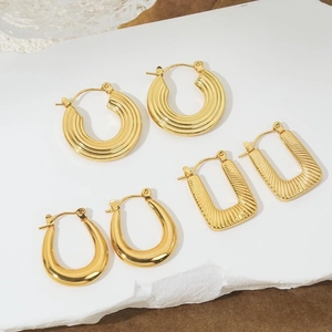 Three pairs of 18K gold-plated stainless steel earrings on a white marble stone surface