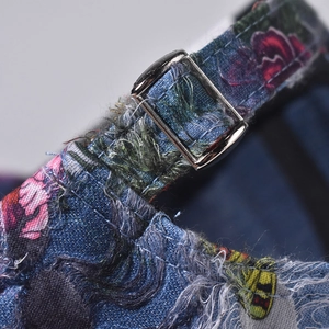 Detail of adjustable silver buckle on distressed floral denim baseball cap