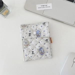Close-up of quilted floral sanitary bag with snap button closure on minimalist desk