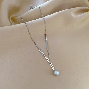 Macro detail of silver minimalist titanium steel necklace with matte spherical pendant