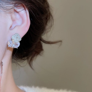 Détail macro de boucles d'oreilles fleurs en argent avec zircon ovale sur le modèle