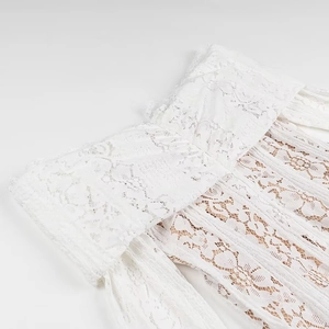Close-up of intricate white crochet lace neckline detail with soft nude lining texture