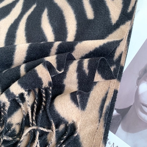 Detail shot of the khaki animal print scarf with fringe edges and premium soft texture