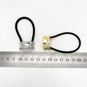 Detailed view of elastic hair ties with gold and silver alloy plates next to a ruler