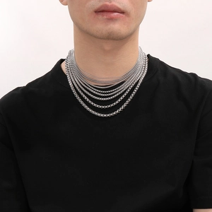 Close-up of layered silver stainless steel chain necklaces worn on a black t-shirt