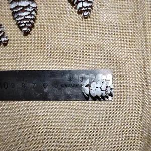 Detail of snowy white pine cone decoration on burlap with ruler showing 3.5cm size