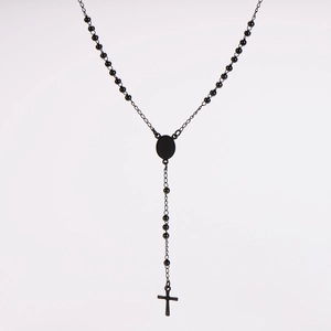 Dettaglio ravvicinato di una collana lunga a grani neri con un ciondolo a forma di croce