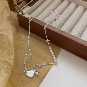 S925 silver necklace with heart, pearl, and cross charms on a vintage wooden jewelry box
