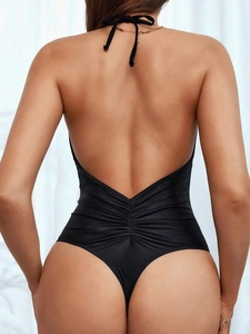 Detail of black halter swimsuit featuring backless deep V-cut and ruched waist detail