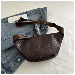 Detail of brown woven chest bag on denim jacket with textured fabric background