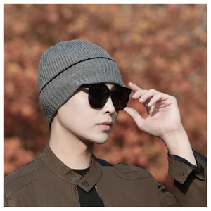 Close-up of a men's gray ribbed knit beanie with black stripes worn outdoors