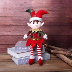 Christmas plush long-legged elf doll in red and green festive outfit on wooden books