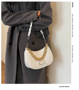 Detail view of white underarm bag with thick gold chain and stylish woven shoulder strap