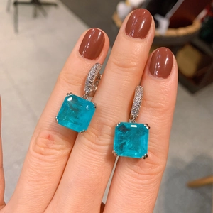 Close-up of square emerald-cut Paraiba blue earrings with silver pave zircon accents