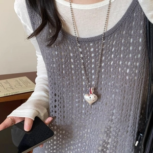 Silver heart pendant necklace with beaded chain on a model wearing grey knit vest