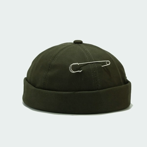 Detail of olive green docker hat with silver pin accent on smooth canvas fabric