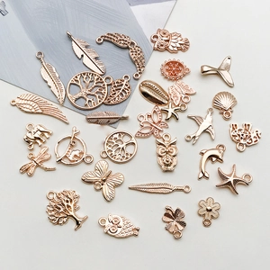 Macro detail of 28 rose gold zinc alloy charms including feathers and trees for DIY jewelry