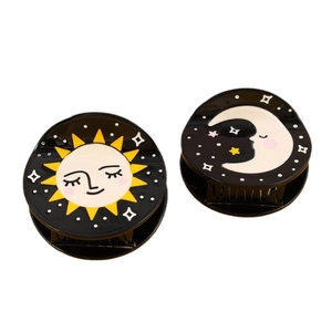 Set of two black acetate hair claws with celestial sun and moon patterns in a round shape