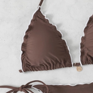 Close-up of chocolate brown bikini with white ruffle trim and gold pendant detail