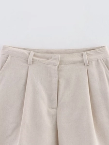 Detail of linen blend shorts featuring waist pleats and durable fabric texture