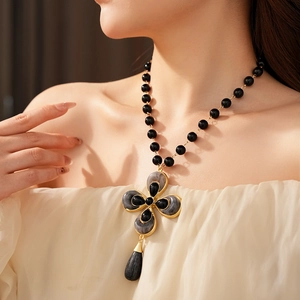 Detail of vintage flower teardrop necklace with gold frame and black beads on model