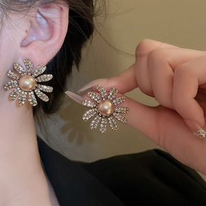 Close-up of golden daisy earrings featuring elegant pearls and sparkling rhinestones