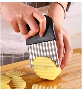 Action shot of the stainless steel crinkle cutter slicing wave potatoes on a wood board