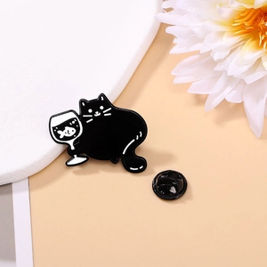 Détail d'un pin's en émail chat noir tenant un verre de poisson sur fond floral doux