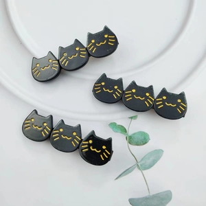 Detailed view of three cute black acetate cat hair clips arranged on a white ceramic plate