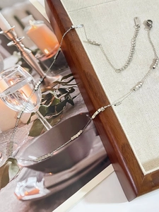 Detail of silver titanium steel necklace with square beads on a lifestyle magazine