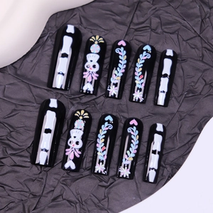 Faux ongles d'Halloween longs avec motifs squelettes et fleurs colorées sur fond noir