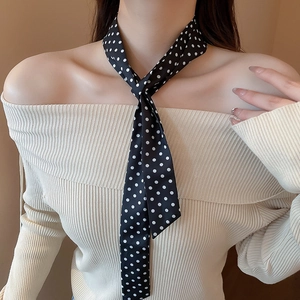 Close-up of a slim black scarf with white polka dots worn elegantly on the neck