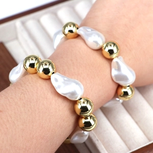 Adjustable gold bead and irregular white pearl bracelet displayed on a jewelry box