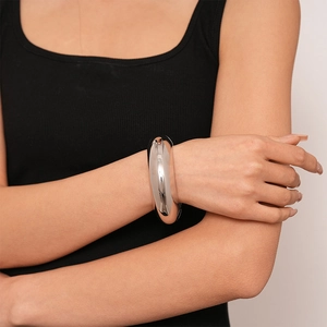 Close-up of a wide polished silver cuff bracelet with mirror finish on woman's wrist