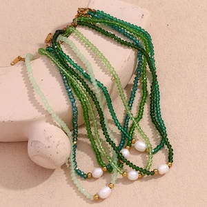 Multilayer beaded necklace with green crystals, pearls and gold clasp on a stand