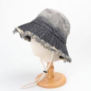 Détail des bords effilochés et du lavage en dégradé d'un chapeau bob en denim