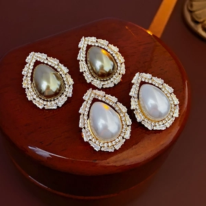 Detail of drop-shaped earrings with white and black pearls and sparkling diamond accents