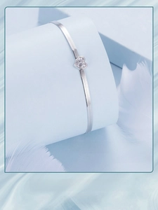 Macro detail of silver heart bracelet with cubic zirconia on a flat snake chain