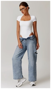 Dettaglio body bianco a costine con scollo quadrato in pizzo e jeans denim azzurri strappati