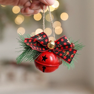 Red metal Christmas bell with plaid bow and pine needles on warm bokeh background
