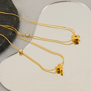 Golden titanium steel necklace with zircon heart and C-letter pendants on mirror