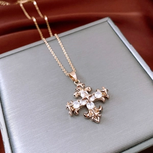 Detailed macro shot of rose gold cross pendant with fleur-de-lis and zircon inlay