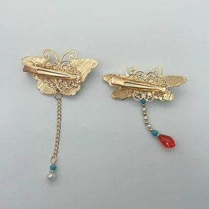 Detail of golden butterfly hair clips with pearl tassels and colorful crystal beads