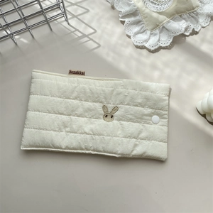 Close-up of quilted cream storage bag with rabbit embroidery and white snap button